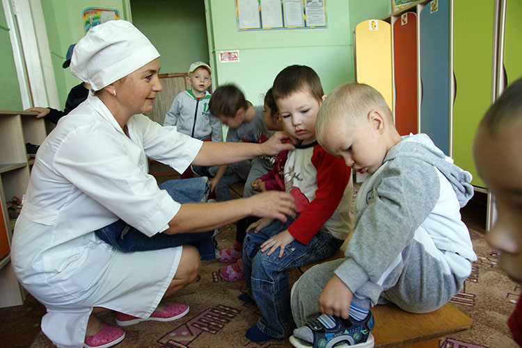После утреннего приема детей младший воспитатель Наталья Алексеевна Маринкова помогает ребятам переодеться 