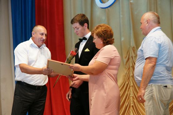 Юрий Ревякин награждает медалиста СОШ № 11 Евгения Бельского и его родителей